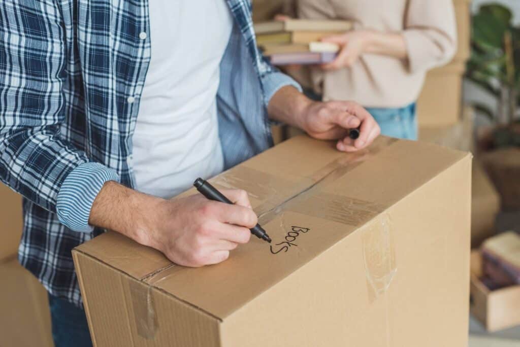 A man is packing and labeling the boxes for moving house